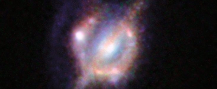 Kolidující galaxie ve vzdáleném vesmíru zobrazené gravitační čočkou