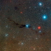Panoramica della nube oscura Lupus 3 e delle giovani stelle calde ad essa associate.