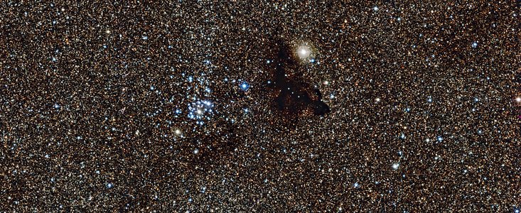 Den starkt lysande stjärnhopen NGC 6520 och det underligt formade molnet Barnard 86