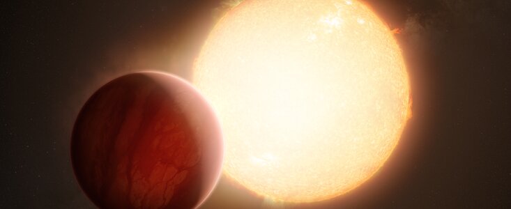 This image shows an artistic view of a bright yellow star and a large red planet, which partially obscures the star from the viewer. The side of the planet facing the star is brightly lit and the other side is in shadow. The gaseous atmosphere of the planet is visible and as a hazy glow around it.
