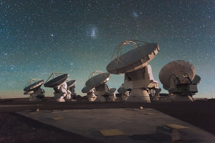 Anteny Atacama Large Millimeter/submillimeter Array (ALMA) w nocy, pod Obłokami Magellana